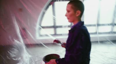 a young boy in a purple shirt painting a wall