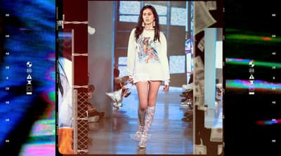 a woman walking down a runway in a white dress