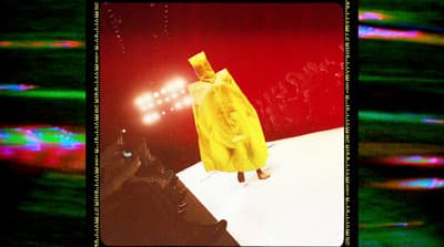 a person in a yellow raincoat walking on a runway