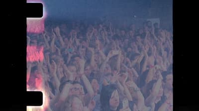 a crowd of people at a concert with their hands in the air