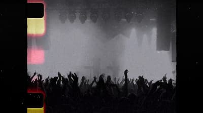 a crowd of people at a concert with their hands in the air