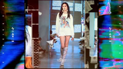 a woman walking down a runway in a white dress